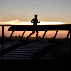 A person running on a treadmill with a background of a sunrise.