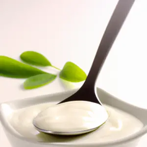 A bowl of yogurt with a spoon and a green leaf garnish.