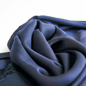 A close-up of a crisp, navy blue scarf draped over a white background.